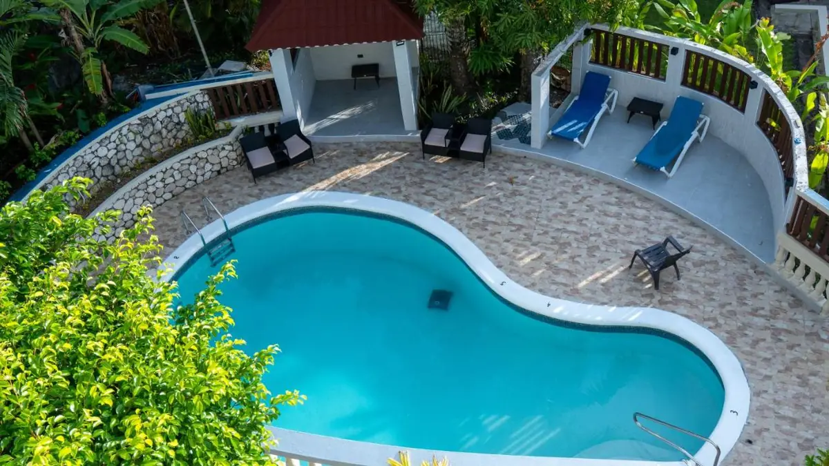 The pool at The Match Resort seen from above, with sun loungers and garden